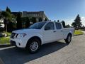 A 2015 Nissan Frontier pickup truck in white color with four doors and silver alloy wheels parked on a road