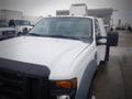 A 2008 Ford F-550 truck with a white exterior and an extended cab is parked with orange clearance lights on the roof and a black front grille