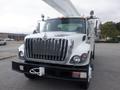 A 2009 International 7400 bucket truck with a white exterior and prominent chrome grille designed for tree trimming and utility maintenance