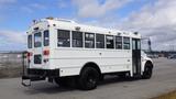 A white 2015 International PC105 school bus with large windows and black wheels parked on a concrete surface