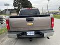 A 2013 Chevrolet Silverado Hybrid viewed from the rear with a silver exterior and a Chevrolet logo on the tailgate