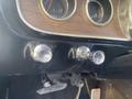 Close-up of the dashboard controls of a 1966 Ford Mustang featuring chrome knobs for wipers and lights with a wooden panel behind them and gauges visible above
