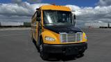 A 2014 Freightliner Thomas Diesel bus with a yellow and black exterior, featuring multiple windows and an orange light on the roof