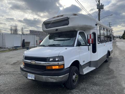 A white 2012 Chevrolet Express with a raised roof and large windows designed for transport