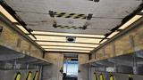 The interior of a 2006 Ford Econoline with metal shelving on both sides and a ceiling that showcases signs and lights