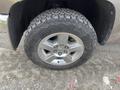 Close-up of a wheel and tire of a 2013 Chevrolet Silverado Hybrid showing the alloy rim and rugged tread pattern