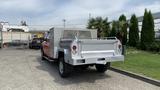 Red 2013 RAM 2500 with a silver flatbed and storage compartments in the back parked on a concrete surface