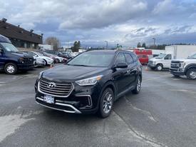 A 2017 Hyundai Santa Fe in black color parked at a lot with other vehicles in the background