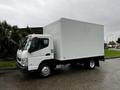 A white 2012 Mitsubishi Fuso FE truck with a boxy cargo area and a single orange light on the roof