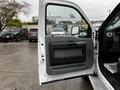 A 2014 Ford F-550 truck with an open driver's side door showing the interior handle and storage compartment