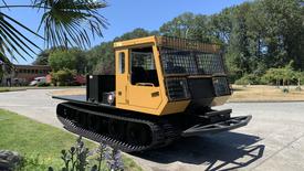 A 2015 PowerBully Tracked Flat Deck Equipment Carrier with a yellow cabin and black tracks designed for transporting heavy equipment