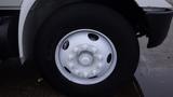 A white wheel with a central hub and numerous bolts on a 2005 International 4300 truck tire