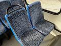 A pair of blue and patterned fabric seats designed for a bus or van interior with a black armrest on one side