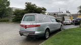 A silver 2013 Lincoln MKT styled as a hearse with a sleek design and chrome accents parked on a paved surface