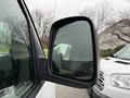 A side mirror of a 2009 Chevrolet Express with raindrops visibly on the surface