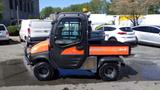 A 2013 Kubota RTV 1100 utility vehicle with an orange body and black accents featuring four wheel drive and small tires suitable for off-road use