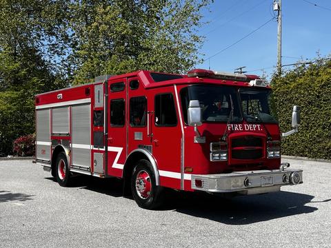A red 2006 Emergency One fire truck with a prominent front grille and fire department markings on the side, featuring flashing lights on top and large wheels