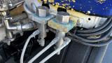 Close-up of hydraulic control valves with metal fittings and braided hoses attached to a 2006 Ford LCF 550 truck