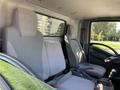 Interior view of a 2015 Isuzu NPR with two gray cloth seats and a central console in the foreground