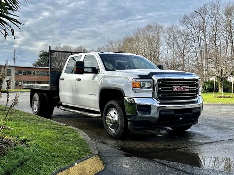 A 2017 GMC Sierra 3500HD pickup truck with a flatbed and chrome grille parked on a road