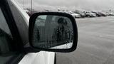 A close-up view of the side mirror of a 2016 Nissan Frontier with raindrops on the surface