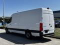 A white 2022 Mercedes-Benz Sprinter van with a long cargo area and a rear door parked on a roadside