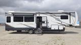 A 2021 Forest River Cedar Creek travel trailer with a gray and white exterior featuring large windows and an entry door on the side