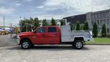 A red 2013 RAM 2500 truck with a flatbed and utility body parked on a concrete surface