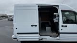 A white 2012 Ford Transit van with an open sliding side door revealing the interior and seating area