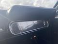 The interior dashboard of a 1966 Ford Mustang featuring a chrome trimmed glove compartment with a small Mustang emblem