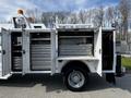 A white 2018 Ford F-550 with open side compartments displaying organized metal drawers and shelves