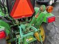 A 2003 John Deere 790 tractor showcasing its hydraulic lift and control mechanisms in green with red reflector and warning sign