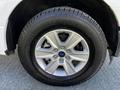 A close-up of a silver alloy wheel of a 2017 Ford F-150 with a black tire showing tread detail and the Ford logo in the center hub