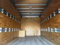 Empty interior of a 2017 Isuzu NPR truck with wood paneling and metal strips along the walls