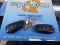 Two black key fobs with buttons and a metal key attached, resting on a blue repo.com branded surface