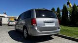 A silver 2016 Dodge Grand Caravan is parked with its rear visible showcasing a simple design and clear taillights