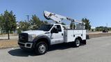 A white 2011 Ford F-450 SD utility truck with a mounted aerial lift and storage compartments on the sides