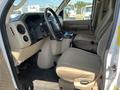 Interior view of a 2012 Ford Econoline van showing the driver's seat and dashboard with controls and cup holders