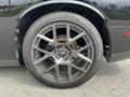 A close-up of a black alloy wheel from a 2017 Dodge Challenger with a distinctive multi-spoke design and performance tire mounted on it