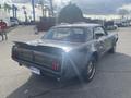 A 1966 Ford Mustang with a sleek design features a dark exterior and distinctive rear tail lights showcasing a classic car look