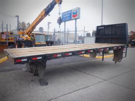 A 2000 flat deck trailer with wooden planks on top and two sturdy legs for support