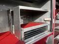 The image shows metal storage shelves inside a 1994 Freightliner FL80 with a red rubber mat on the floor and a textured metal surface on the shelves