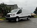 A white 2016 Ford Transit van with a refrigeration unit on top parked on the street