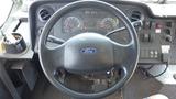 Close-up of the steering wheel and dashboard of a 2011 Ford Econoline showing the Ford emblem gauges and control buttons