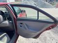 A red 2007 Toyota Camry Hybrid with an open front door showing the interior features and seating