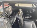 Interior view of a 1966 Ford Mustang showing black leather seats with horizontal stitching a classic steering wheel and seatbelts