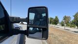 A side mirror of a 2011 Ford F-450 SD showing a reflection of the truck's interior and the outside environment