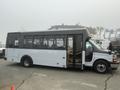 A 2017 Chevrolet Express bus with a white exterior and large windows is parked with its side door open