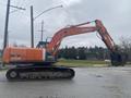 A 2006 Hitachi ZX200LC excavator with an orange and black design featuring a large bucket at the front and tracks for movement