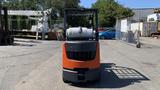 A 2018 Toyota 8FGCU25 forklift with an orange and black design featuring a raised fork and a propane tank positioned at the back